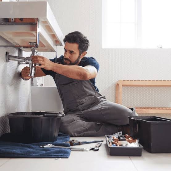 Fontanero trabajando bajo el fregadero de una vivienda en Madrid