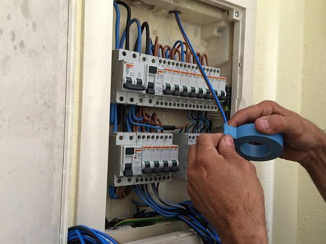 Manos de electricista ajustando un automático del cuadro