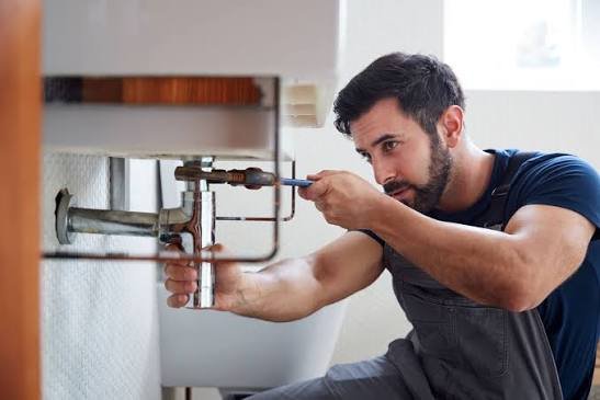 Fontanero cambiando una tubería bajo el lavabo