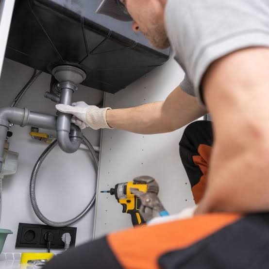 Fontanero apretando la tuerca de un sifón bajo el lavabo